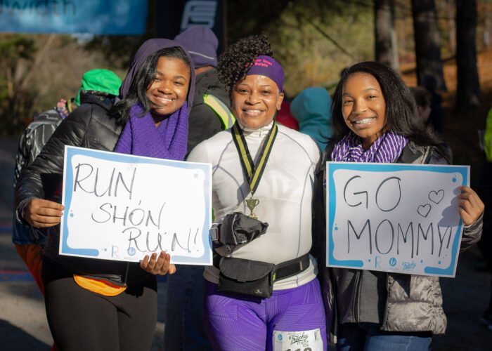 Runners at Trophy Trot holding signs for mom