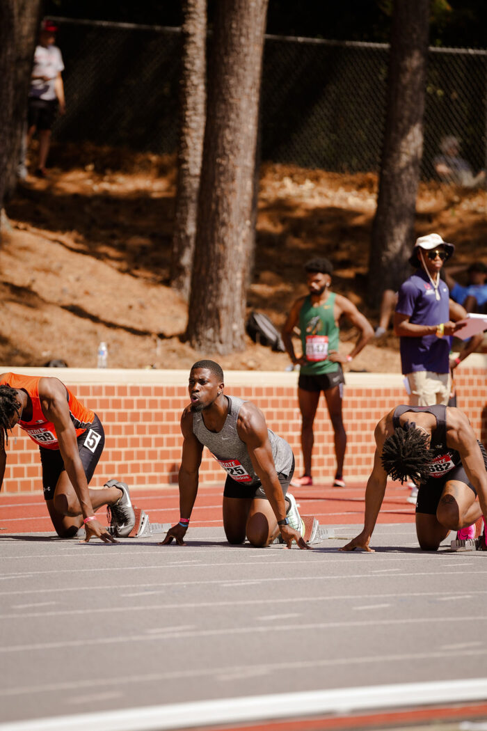 Men track runners preparing to race on the track.