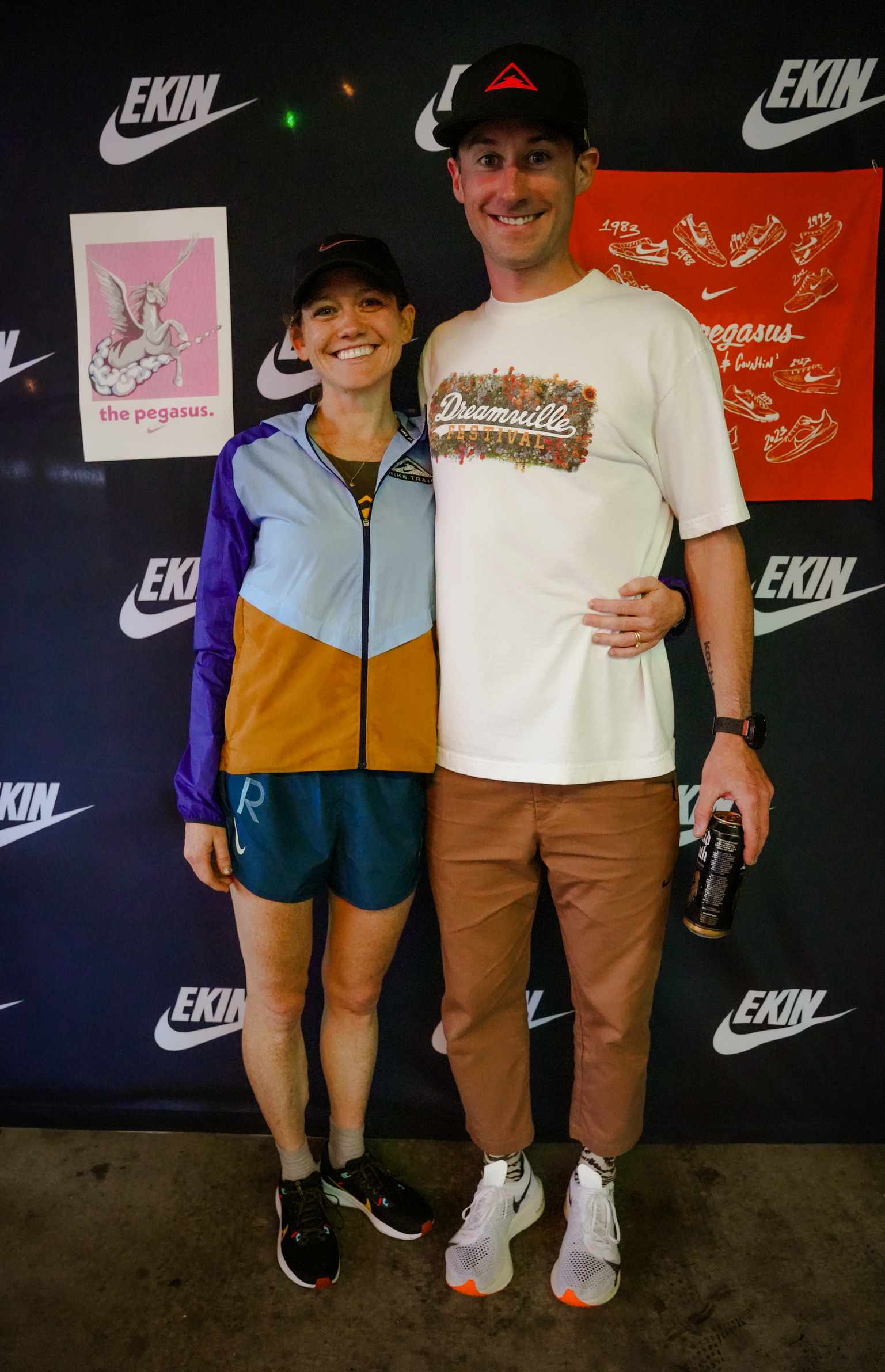 two people standing in front of a nike wall