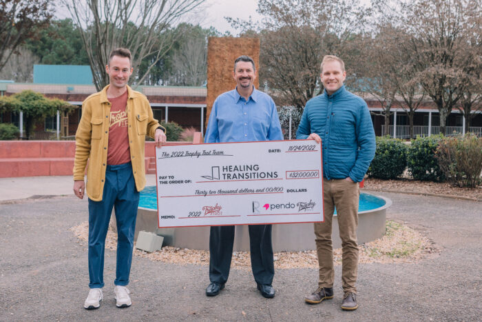 Three men holding a large donation check to Healing Transitions