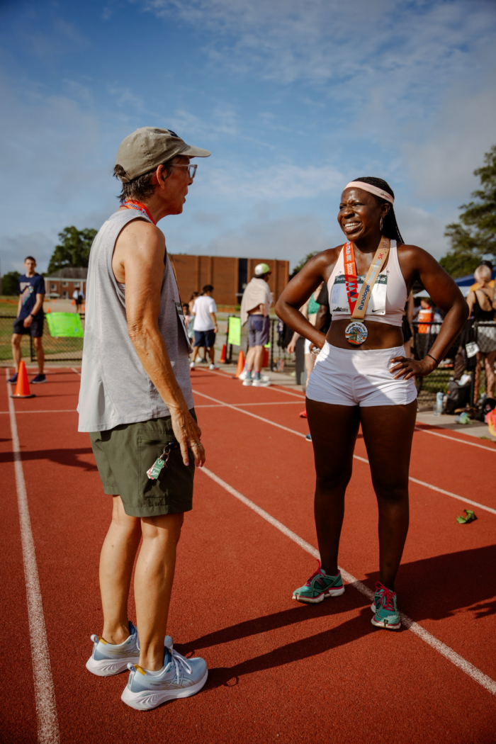 A woman and a man talk and celebrate their 5k on a track. From RTC 5k. 